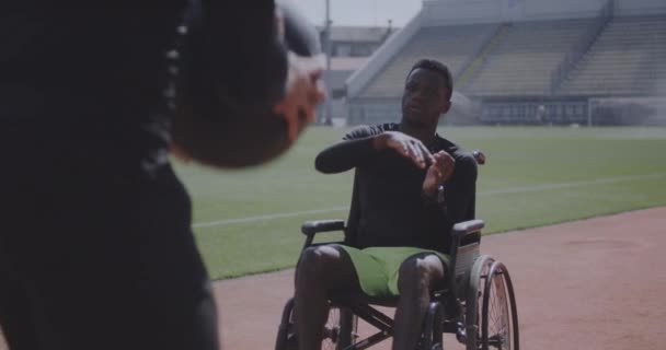 車椅子のアスリートとトレーナーが薬のボールを投げる — ストック動画
