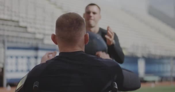 Wheelchaired athlete and trainer throwing medicine ball — Stock Video