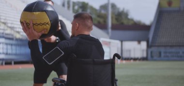 Tekerlekli sandalyeli atlet ve eğitmen ilaç topu atma