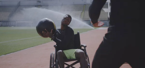 Wheelchaired athlete and trainer throwing medicine ball — Stock Photo, Image