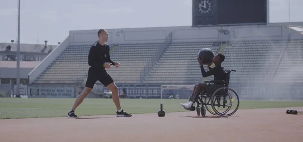 Atleta con ruedas y entrenador lanzando balón medicinal — Foto de Stock