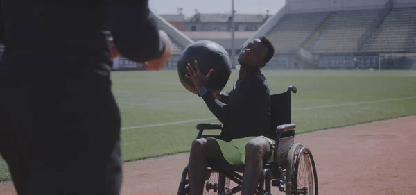 Wheelchaired athlete and trainer throwing medicine ball — Stock Photo, Image