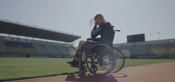 Disabled athlete sitting in wheelchair by a sports field — Stock Photo, Image