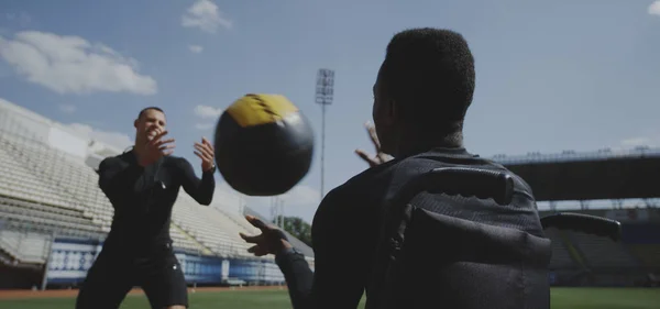 Wheelchaired athlete and trainer throwing medicine ball