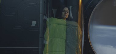 Dişi astronot cam bir kapsülde uyuyor.