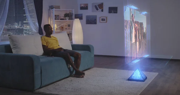 Hombre viendo la televisión holográfica por la noche — Foto de Stock