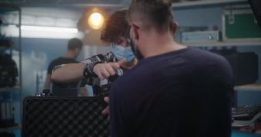 Tezgahtar dükkandaki video ekipmanlarını açıklıyor.