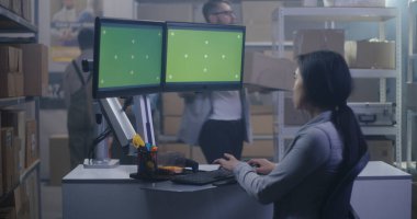 Dağıtım merkezinde bilgisayar başında çalışan genç bir kadın.