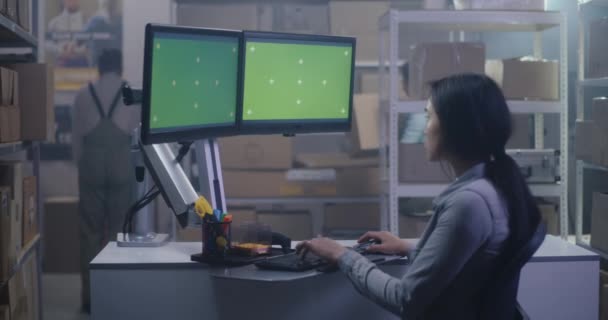 Mujer joven que trabaja en una computadora en un centro de distribución — Vídeos de Stock