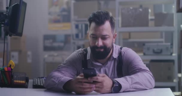 Werknemer die zijn smartphone gebruikt in een distributiecentrum — Stockvideo