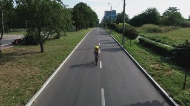 Bisikletli kurye yolda bisiklet sürüyor.