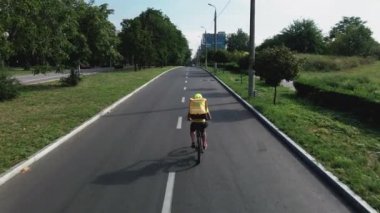 Bisikletli kurye yolda bisiklet sürüyor.