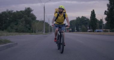 Bisikletli kurye yolda bisiklet sürüyor.