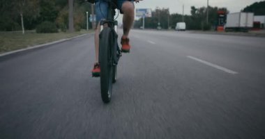 Bisikletli kurye yolda bisiklet sürüyor.