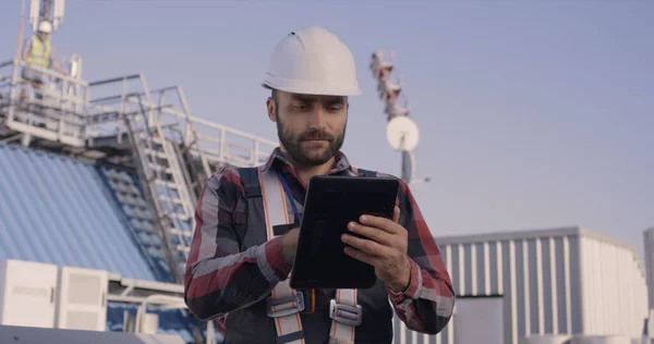 Ingenieros usando una tableta en una torre celular — Foto de Stock