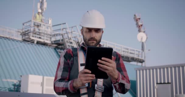 Ingegneri che utilizzano un tablet su una torre cellulare — Video Stock