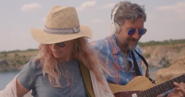 Muž a žena hrají na kytary na louce — Stock video