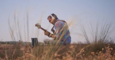 Müzisyen dışarıda bas gitar çalar.
