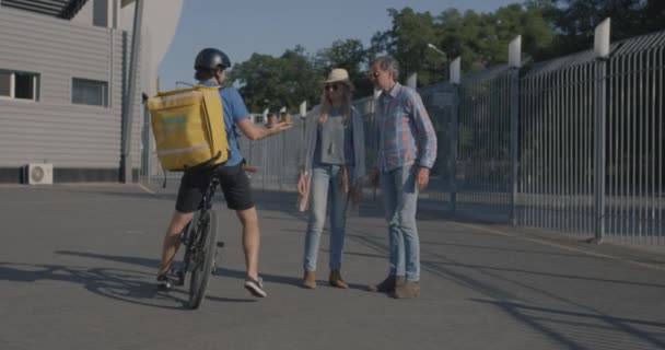 自転車のメッセンジャーはカップルに食べ物を提供します — ストック動画