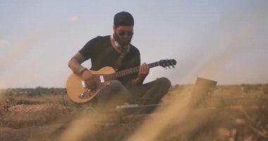 Müzisyen elektro gitar çalar ve elektronik kullanır