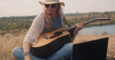 Dizüstü bilgisayar kullanan kadın gitarist