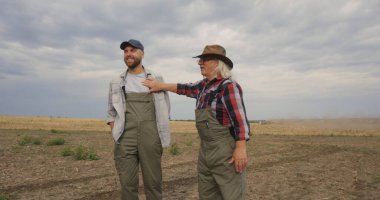 Mutlu kıdemli çiftçiler torunlarına tarlayı gösteriyor.