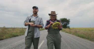 Kırsal yolda yürüyen ayçiçekli çiftçiler