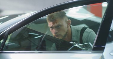 Erkek teknisyen arabanın camından film çıkarıyor.