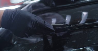 Hasat teknisyeni far ile koruyucu film kesiyor.