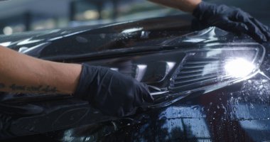 Hasat teknisyeni far ile koruyucu film kesiyor.