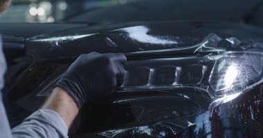 Hasat teknisyeni far ile koruyucu film kesiyor.