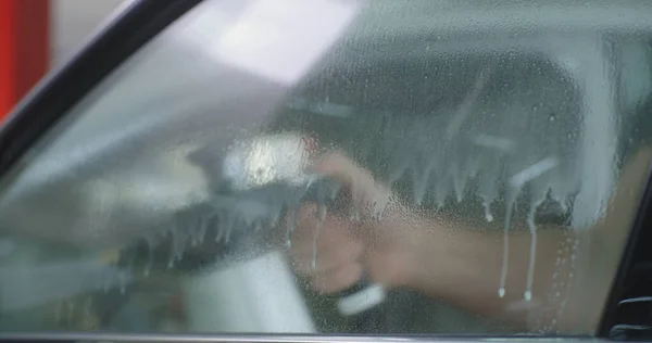 Erkek tamirci arabanın camını yıkıyor. — Stok fotoğraf