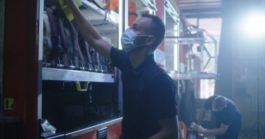 Maskeli itfaiyeci itfaiye arabasını temizliyor.