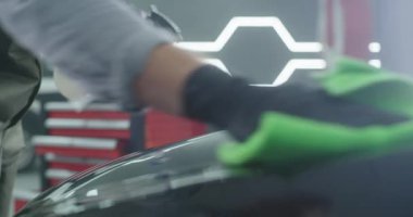 Hasat tamircisi araba kaputunu temizliyor.