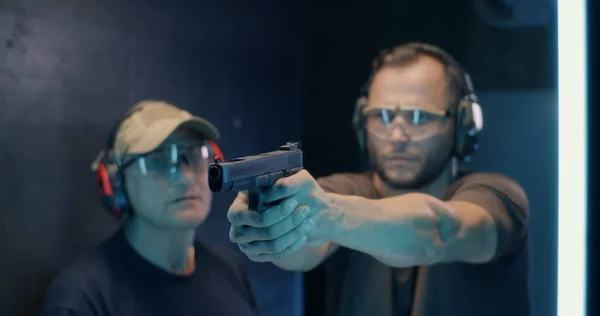 Dojrzałe instruktor uczy człowiek strzelać pistolet — Zdjęcie stockowe