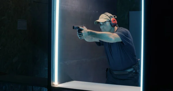 Volwassen schutter schiet pistool in donker bereik — Stockfoto