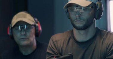 Genç adam antrenörle silah kullanmayı öğreniyor.