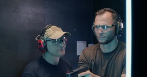 Mature instructor teaching man to shoot pistol — Stock Video