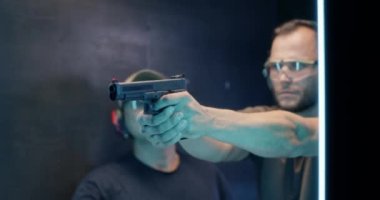 Galeride olgun bir adam tüfekle ateş ediyor.