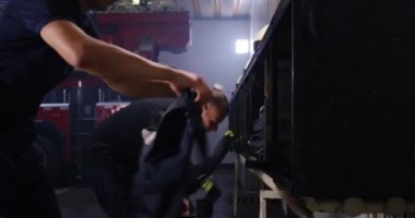 İtfaiyeciler kamyonun yanında üniforma giyiyor.