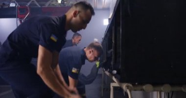 İtfaiyeciler kamyonun yanında üniforma giyiyor.