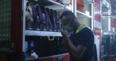 Maskeli itfaiyeci itfaiye arabasını temizliyor.