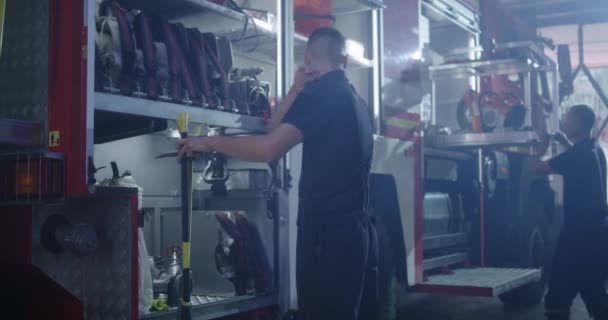 Strażak w masce czyszczący wóz strażacki — Wideo stockowe