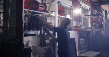 İtfaiyeci itfaiye arabasına hortum takıyor.