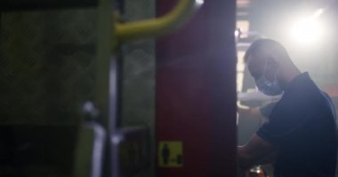 Maskeli itfaiyeci kamyon parçaları yıkıyor.