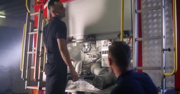 Tűzoltó gyakornok tűzoltó felszerelést tanít — Stock videók
