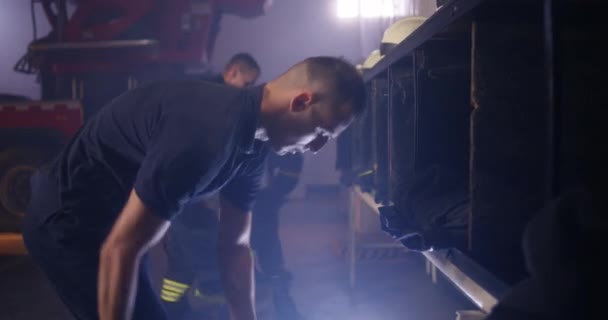 Brandweerlieden trekken uniform aan in de buurt van vrachtwagen — Stockvideo