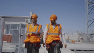 Elektrik santralinde yürüyen ve konuşan erkek mühendisler.
