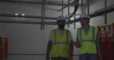 Enerji santralinin içinde yürüyen ve konuşan mühendisler