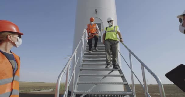 Ingenieros en máscaras alejándose molino de viento — Vídeos de Stock